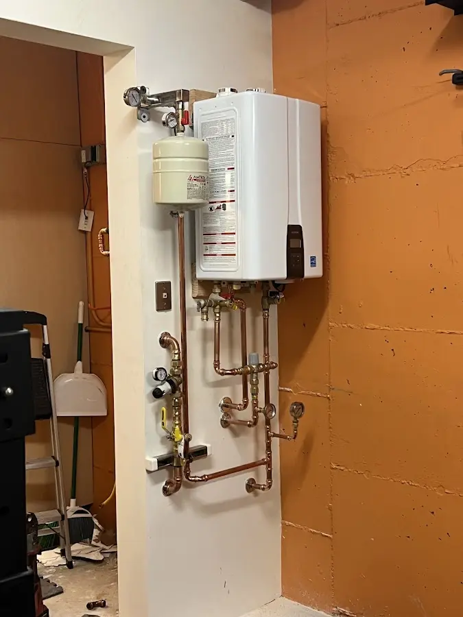 Plumbing technician inspecting water heater connections in Momence